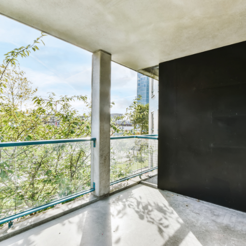 Balkon mit Betonboden und Glasgeländer – modernes Design und lichtdurchflutete Architektur nach Sanierung.