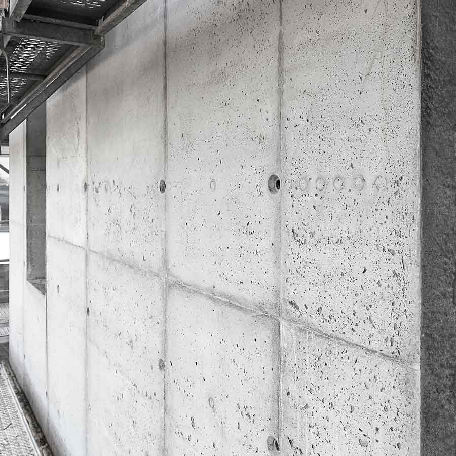 Nahaufnahme einer modernen Sichtbetonfassade mit Plattenfugen und Ankerlöchern, im Bau oder saniert Nahaufnahme einer modernen Sichtbetonfassade mit Plattenfugen und Ankerlöchern, im Bau oder saniert