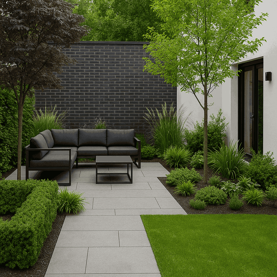 Moderner Garten mit grauen Terrassenplatten, dunkelgrauem Loungesofa und Beistelltisch vor einer schwarzen Ziegelwand. Rechts erstreckt sich eine Rasenfläche, umgeben von Bäumen, Sträuchern und Ziergräsern, die eine entspannte Atmosphäre schaffen. Moderner Garten mit grauen Terrassenplatten, dunkelgrauem Loungesofa und Beistelltisch vor einer schwarzen Ziegelwand. Rechts erstreckt sich eine Rasenfläche, umgeben von Bäumen, Sträuchern und Ziergräsern, die eine entspannte Atmosphäre schaffen.